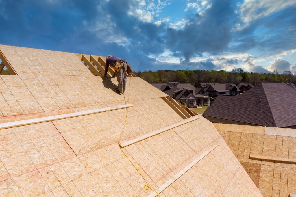 Workers build a roof on the house applying roof plywood panels